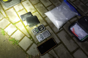 Zdjęcie przedstawia znalezione przedmioty, w tym narkotyki na chodniku.
