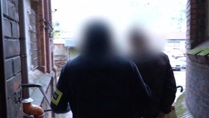 Zdjęcie przedstawia policjanta wraz z zatrzymanym mężczyzną.