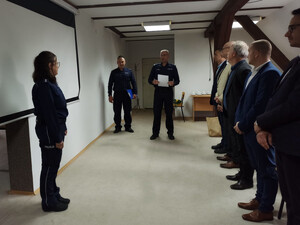 Zdjęcie przedstawia policjantów oraz osoby cywilne w pomieszczeniu.