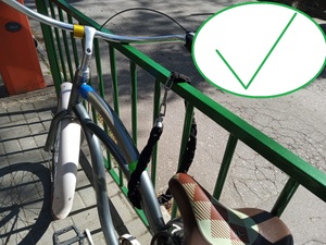 Zdjęcie przedstawia rower przypięty linką do poręczy.