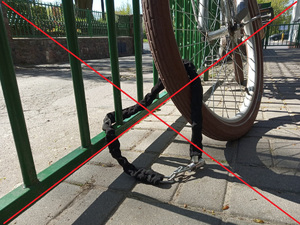 Zdjęcie przedstawia rower przypięty linką do poręczy.