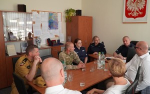 Zdjęcie przedstawia uczestników odprawy służbowej w gabinecie Komendanta Komisariatu Policji w Biskupcu.