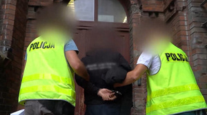 Zdjęcie przedstawia prowadzenie zatrzymanych osób przez nieumundurowanych policjantów.