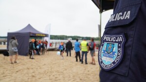 Zdjęcie przedstawia uczestników festynu a na pierwszym planie fragment policyjnego munduru.