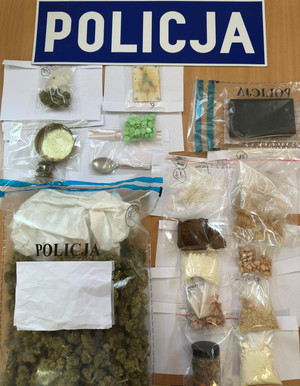 Zdjęcie przedstawia napis policja oraz zabezpieczone narkotyki.