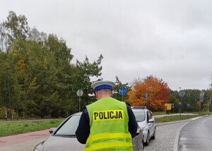 Zdjęcie przedstawia funkcjonariusza podczas kontroli drogowej.