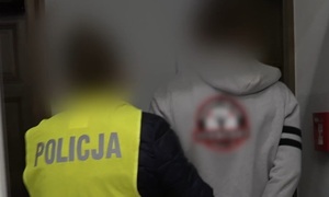 Zdjęcie przedstawia prowadzenie zatrzymanego mężczyzny.