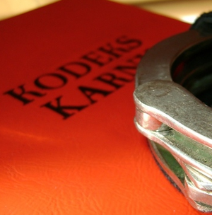 Zdjęcie przedstawia kodeks karny i kajdanki