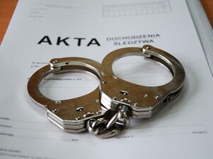 Zdjęcie przedstawia kajdanki oraz akta sprawy