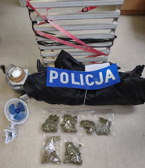 Zabezpieczone narkotyki i sprzęt do uprawy nielegalnych roślin oraz napis &quot;Policja&quot;