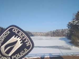 Zdjęcie przedstawia zamarznięte jezioro i napis KMP Olsztyn.