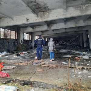 Zdjęcie przedstawia policjanta i pracownika socjalnego podczas kontroli miejsc przebywania osób narażonych na wychłodzenie.