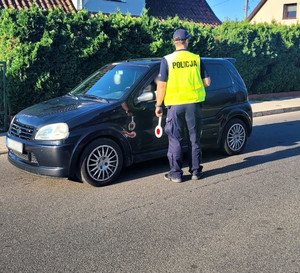 Zdjęcie przedstawia policjanta podczas kontroli drogowej.