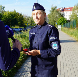 Zdjęcie przedstawia policjantkę udzielającą wywiadu telewizyjnego.