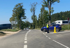 Zdjęcie przedstawia policjanta na drodze i ruch uliczny.