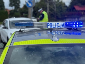 Radiowóz z policjantem w tle
