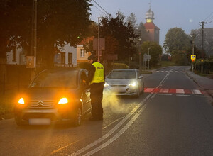 dwa samochody i policjant badający trzeźwość