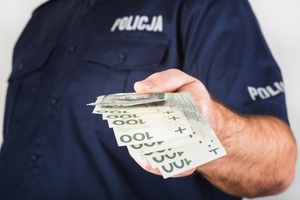policjant trzymający w ręku pieniądze