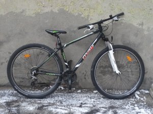 Zdjęcie przedstawia rower koloru czarnego z biało-zielonymi wstawkami.
