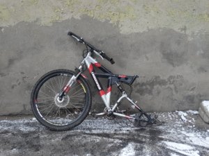 Zdjęcie przedstawia część roweru koloru srebrno-czerwono-czarnego. W rowerze nie ma tylnego koła oraz siodełka.
